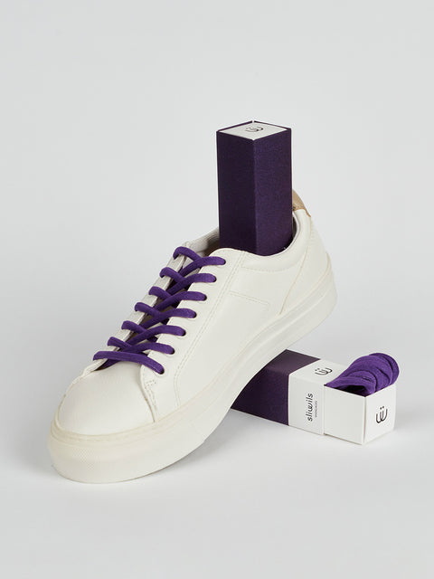 Zapatillas blancas con unos cordones morados en antelina