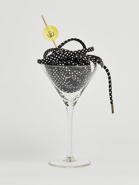 Cordón negro con lunares blancos metido en una copa de cristal