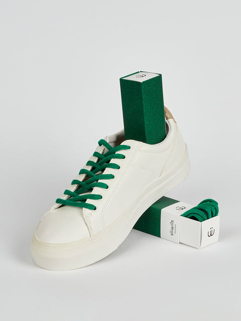 Zapatillas blancas con unos cordones verdes en antelina