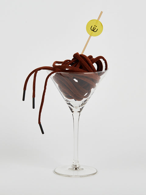 Cordón marrón en antelina metido en una copa de cristal