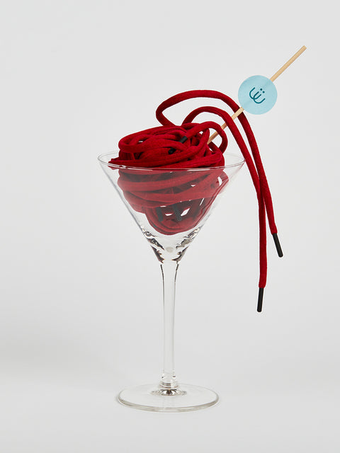 Cordón rojo en antelina metido en una copa de cristal